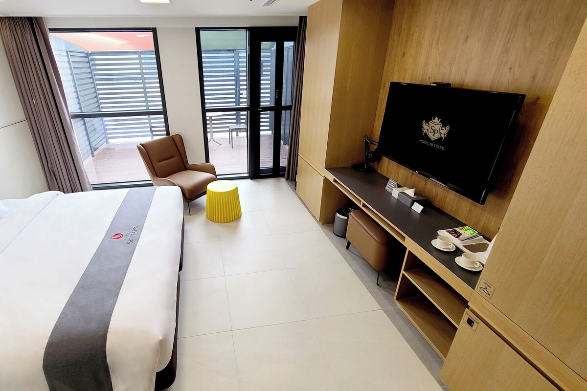 Een hotelkamer met een bed, een televisie, een bureau, een stoel en een tafeltje.