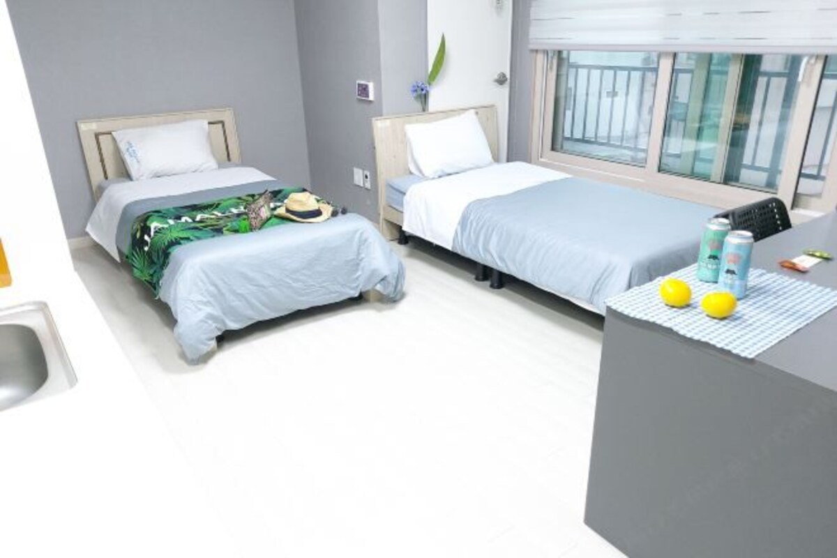 A hotel room with two beds, a small desk, and a window with a view.