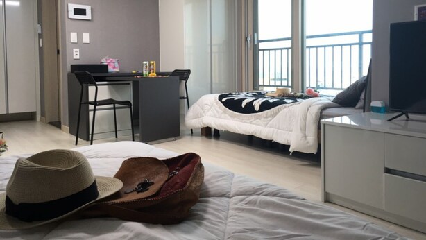 Habitación de hotel con cama, escritorio, silla, televisión y balcón con vistas.