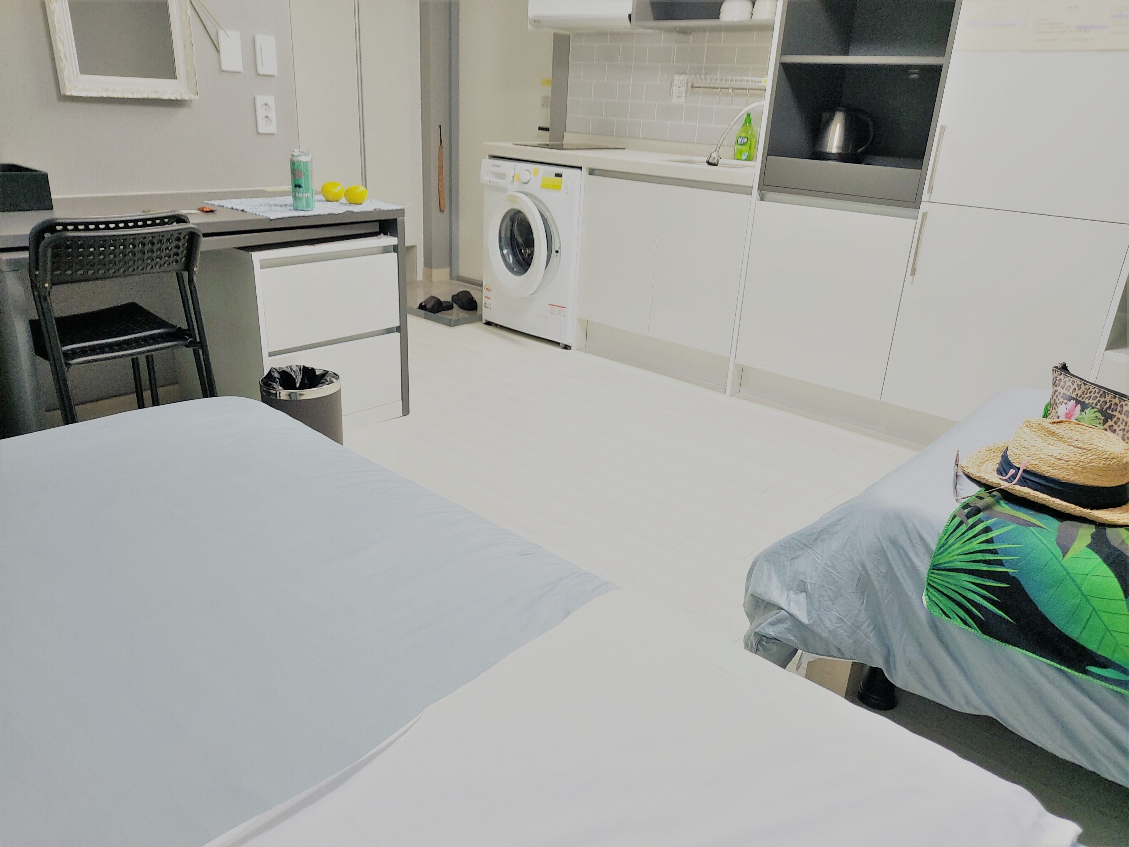 A compact bedroom with a bed, a desk, and a washing machine.