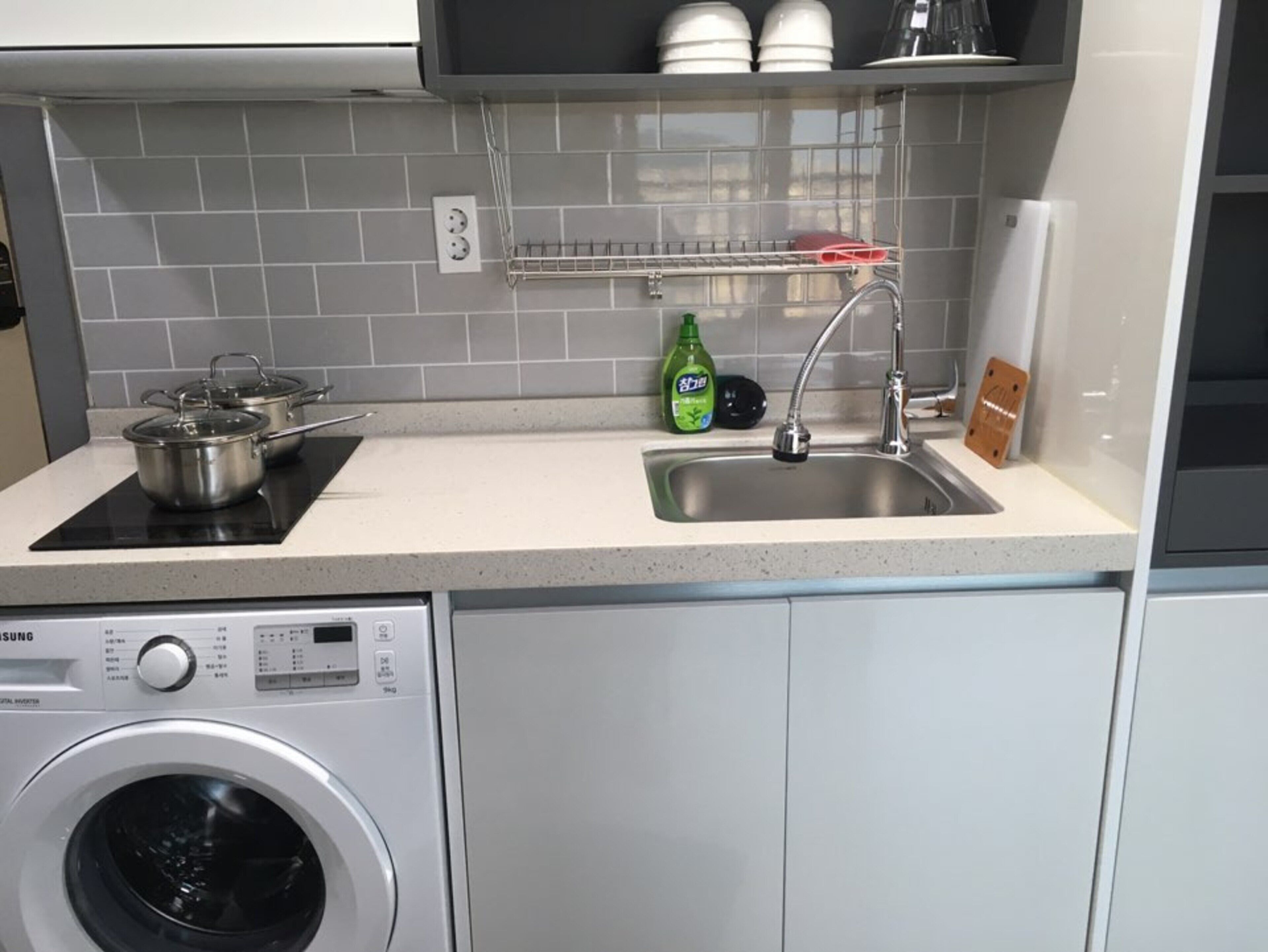 A compact kitchen with a built-in washing machine, a sink, and a dish rack.