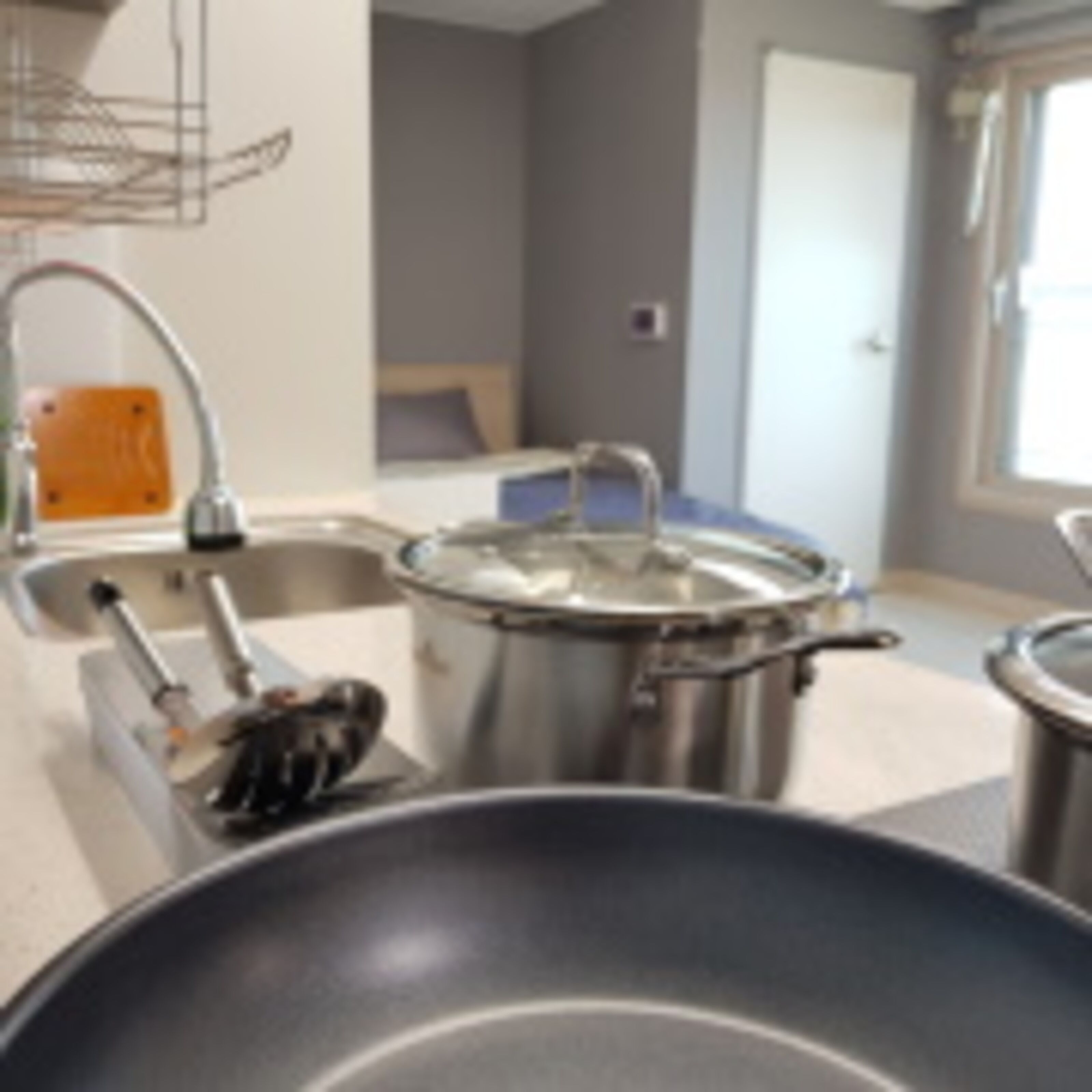 A kitchen with stainless steel appliances, a sink, and a window with curtains.