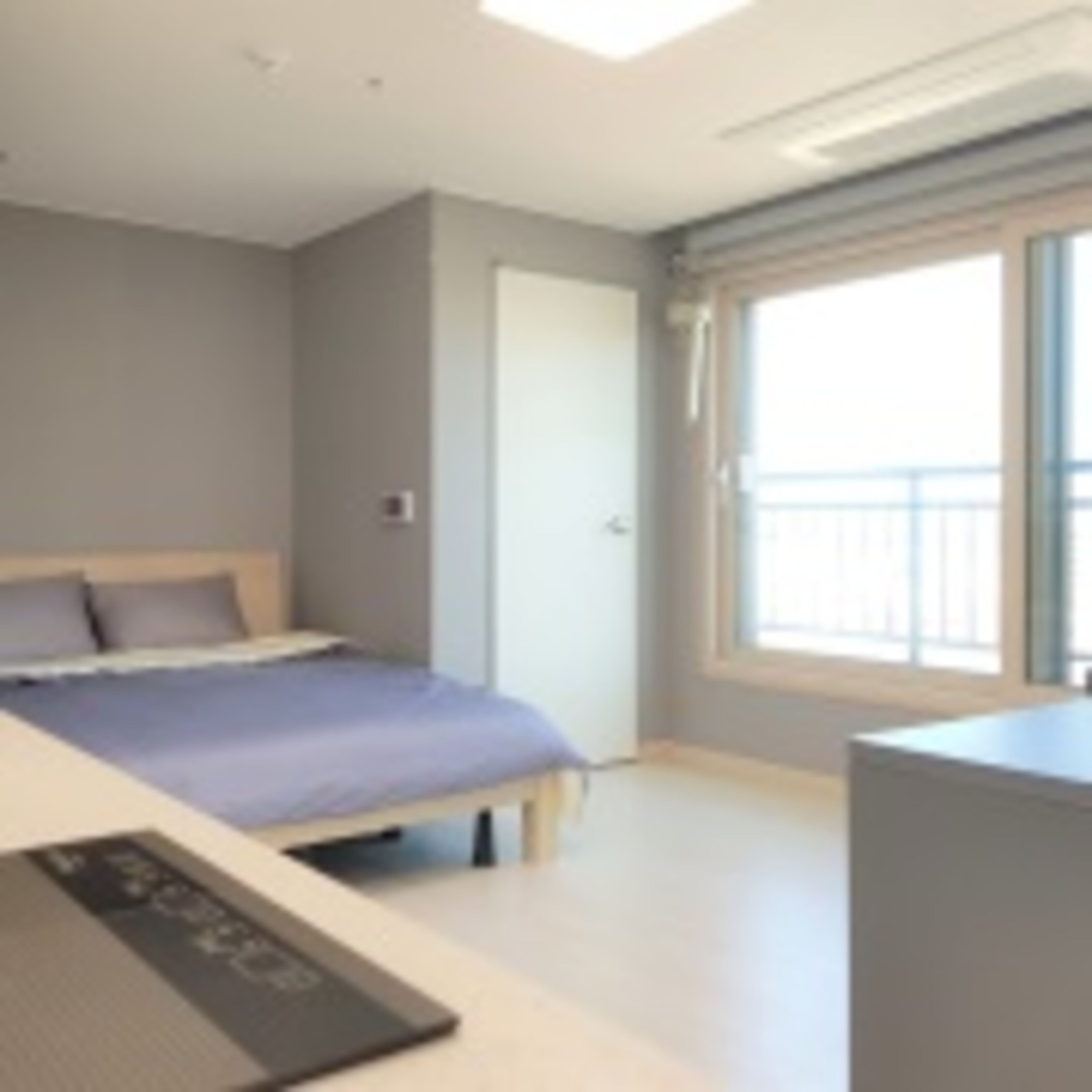 A modern bedroom with a bed, a desk, and a window.