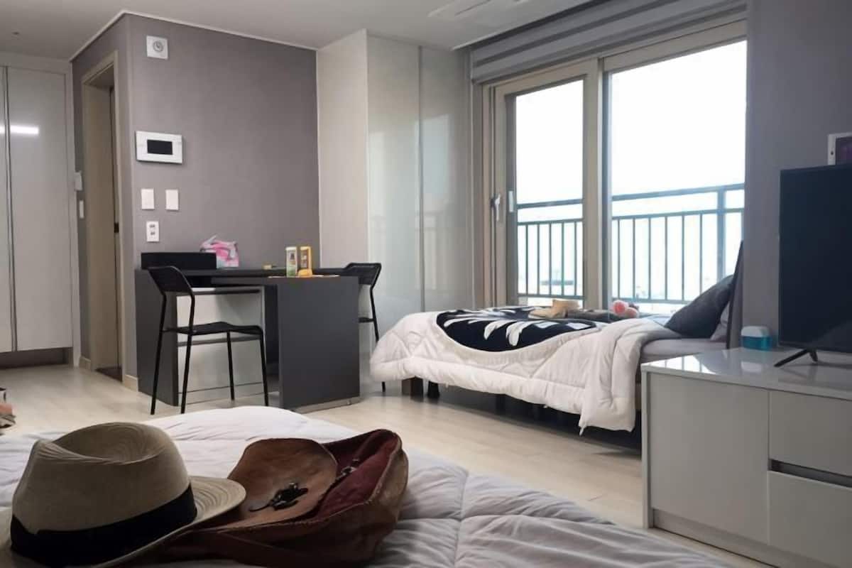 A hotel room with a bed, a desk with a chair, a TV, and a balcony.