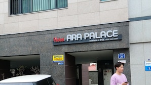 Exterior del Hotel Ara Palace con un coche rojo estacionado frente a él.