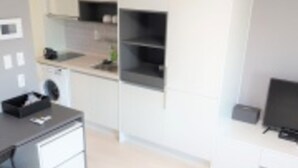 Una cocina moderna con armarios blancos, encimera negra y horno empotrado.
