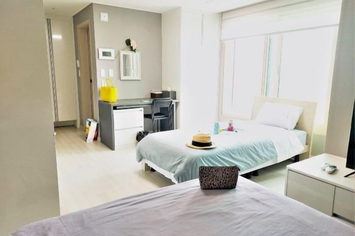 Ein Hotelzimmer mit Bett, Schreibtisch, Stuhl, kleinem Tisch und Fenster.