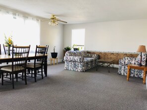 A living room with a dining table, chairs, a sofa, and a ceiling fan.