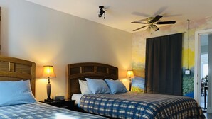 A hotel room with two beds, wooden headboards, and a ceiling fan.