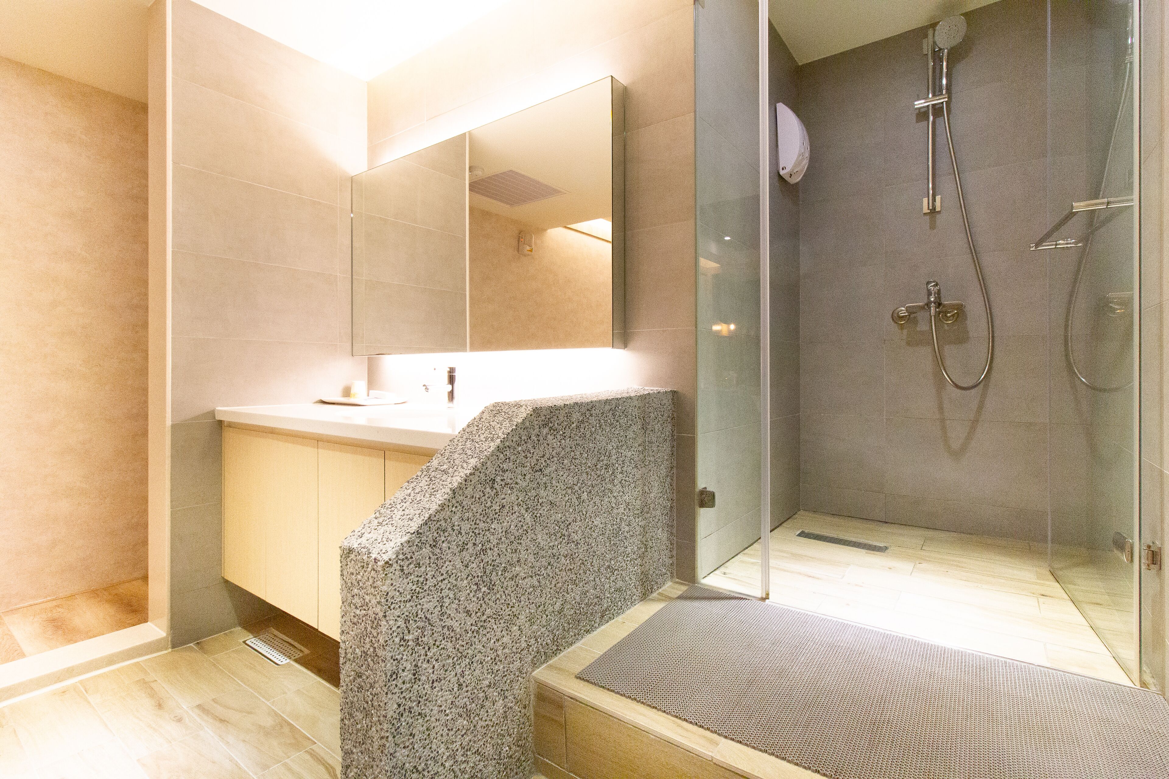 A modern bathroom with a glass shower enclosure, a large mirror, and a granite countertop.