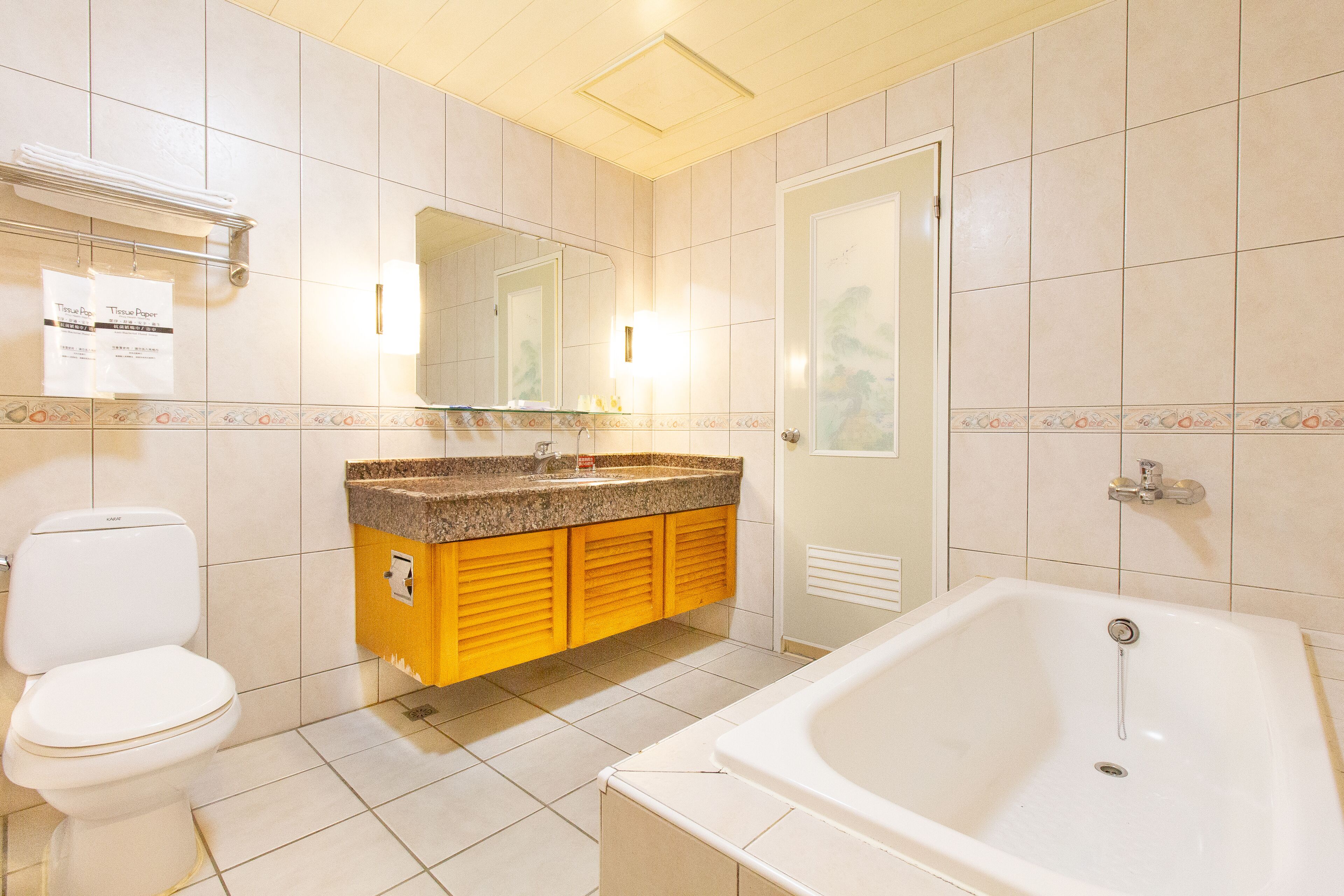 A bathroom with a toilet, sink, mirror, and bathtub.