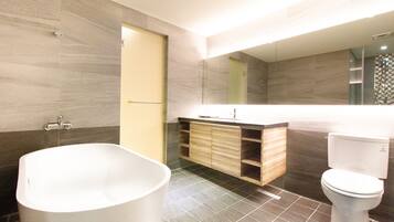 Un baño moderno con una bañera independiente, un inodoro y un lavamanos con espejo.