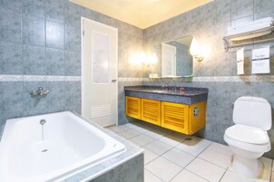 Un baño con bañera, inodoro y tocador con espejo.