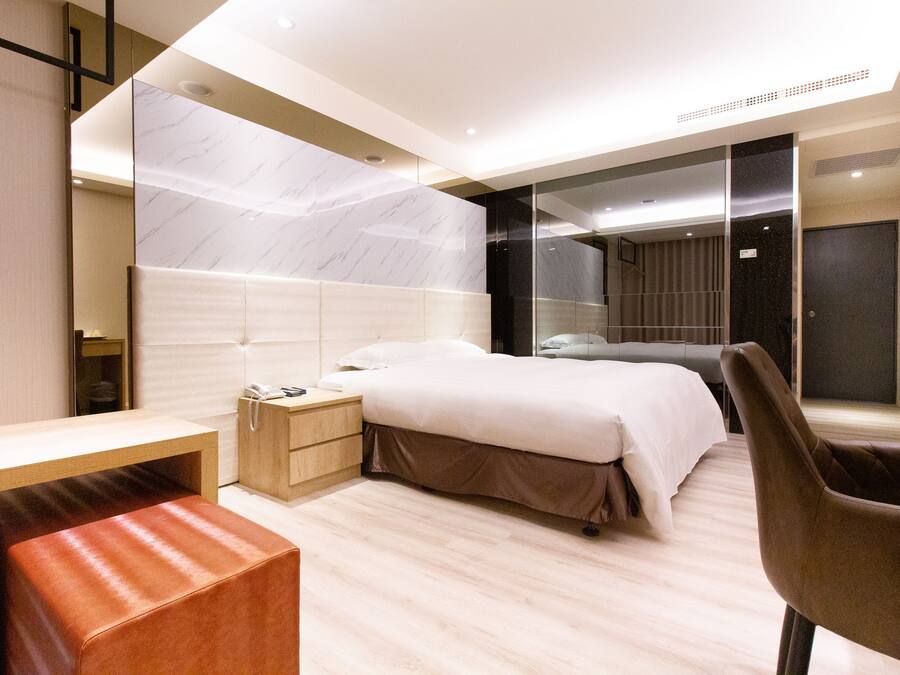 A modern hotel room with a large bed, a desk, and a chair.