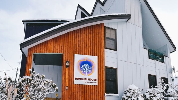 Un edificio moderno con fachada de madera y un letrero que dice "DONGURI HOUSE by Kashiwa Furano".