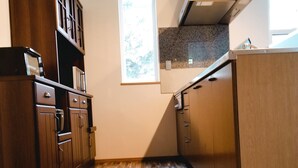 Una cocina con armarios de madera, suelo con motivo de espiga y ventana con vistas a árboles.