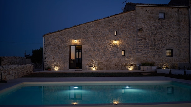 A stone building with a pool, a door, and exterior lighting.