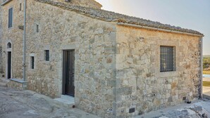 A stone building with a tiled roof, a small window, and a door.