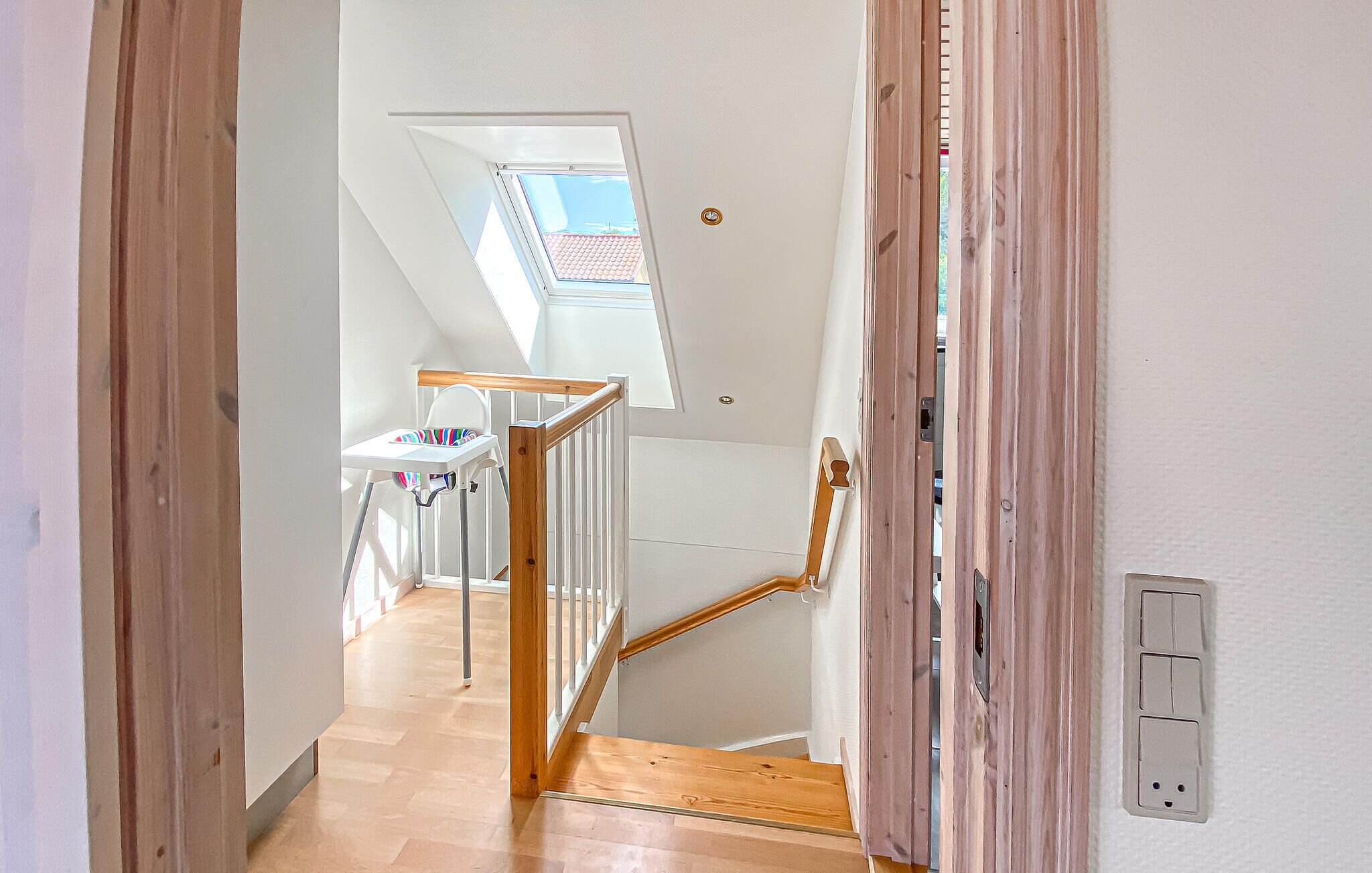 A staircase with wooden railings leading to a room with a skylight.