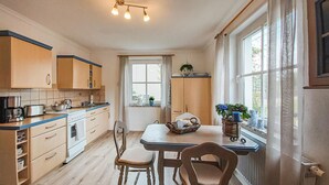 Une cuisine avec des meubles de rangement en bois, une cuisinière et un coin repas comprenant une table et des chaises.