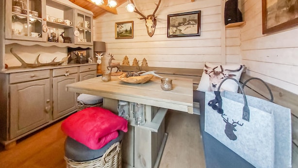 Une cuisine rustique avec des meubles en bois, un lustre, des bois de cerf et un tableau accroché au mur.