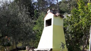 Un patio de piedra con una pared amarilla y un pequeño horno de ladrillo.