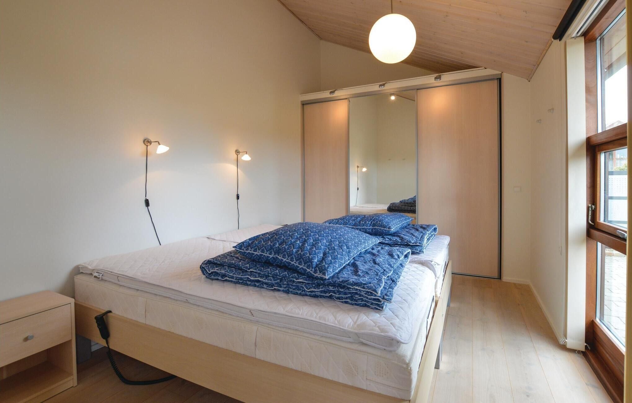 Une chambre à coucher avec un lit, des tables de chevet, un miroir et une fenêtre.