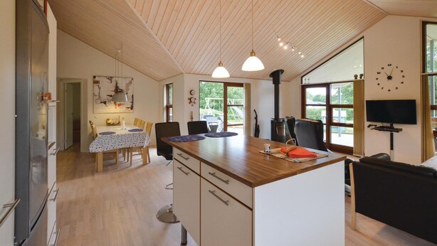 Eine moderne Küche mit Holzboden, ein Essbereich mit Tisch und Stühlen sowie ein großes Fenster, das für natürliches Licht sorgt.