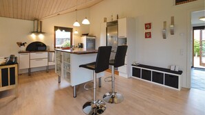 Eine moderne Küche mit Kochinsel, Barhocker und Pendelleuchten.