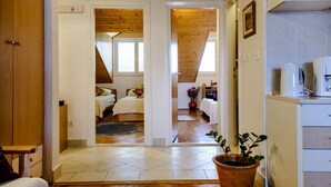 A room with a bed, a wooden ceiling, a potted plant, and a kitchen area with a coffee maker. - Apartment Matic (Dubrovnik)