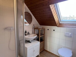 A small, modern bathroom with a skylight, a white sink, and a toilet. - Wohnung Atelier - Willi Ohler Haus (Worpswede)