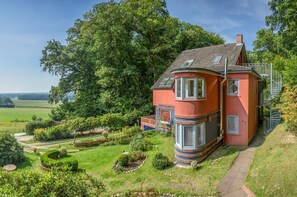 A two-story house with a red facade, a brick base, and a spiral staircase. - Wohnung Atelier - Willi Ohler Haus (Worpswede)