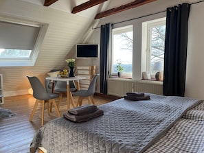 Una habitación acogedora con una cama, un escritorio con silla, un televisor y una ventana con cortinas.