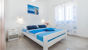 A bedroom with a bed, bedside tables, a nightstand, a wall-mounted light, and a window with sheer curtains. - Gorgeous apartment in Srima with WiFi (Srima)