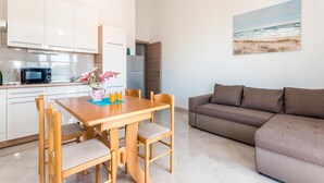 A modern kitchen with white cabinets, a microwave, and a dining area with a wooden table and chairs. - Gorgeous apartment in Srima with WiFi (Srima)