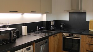 A modern kitchen with a microwave, toaster, coffee maker, and dishwasher. - Beautiful apartment facing Prorel. In the town center. (Briançon)