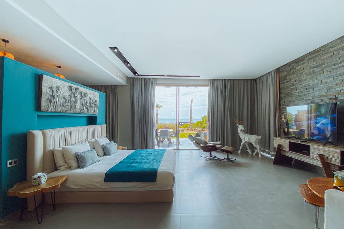Une chambre d’hôtel moderne dotée d’un grand lit, d’une télévision, d’un coin salon et offrant une vue sur l’extérieur.