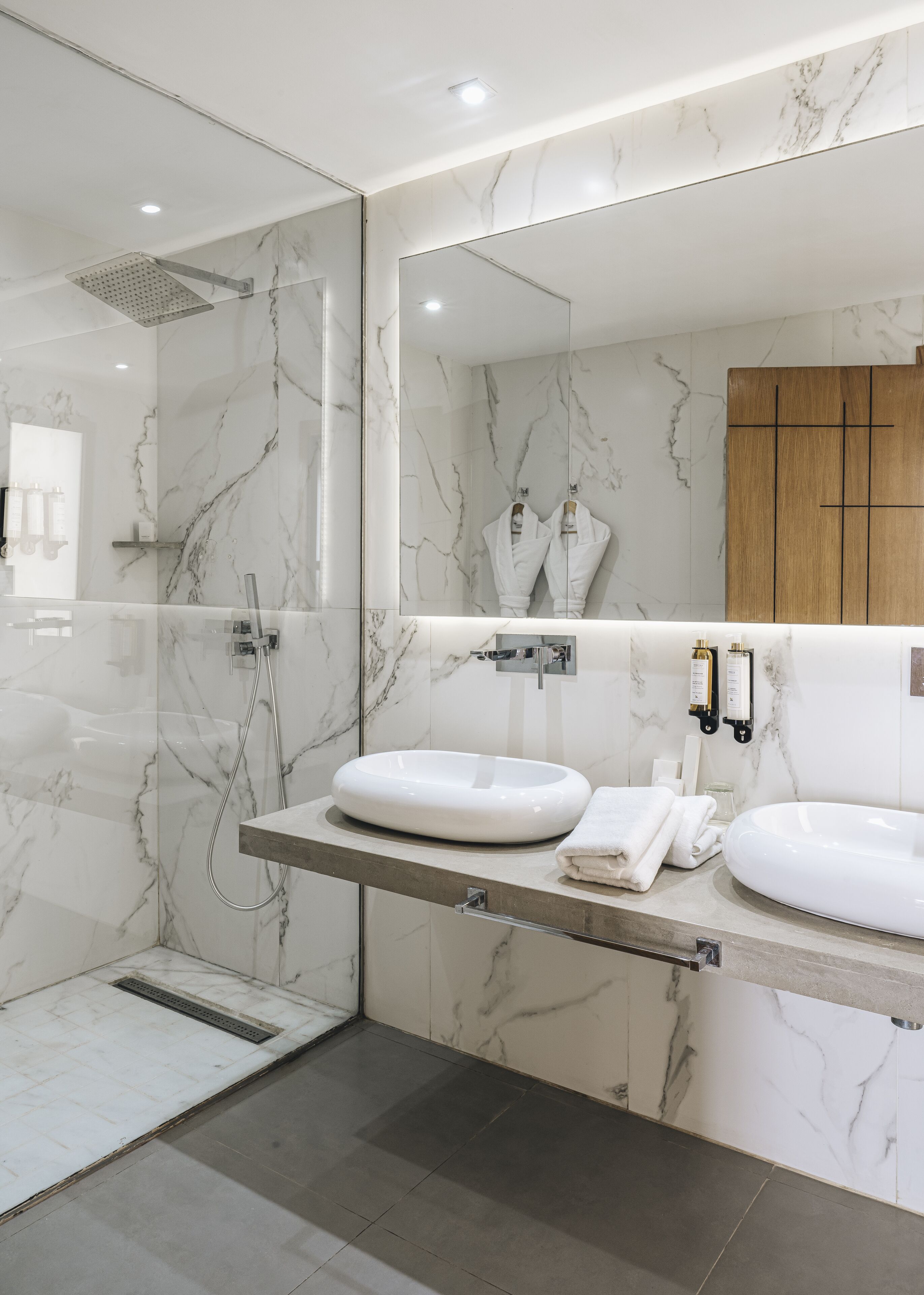 A modern bathroom with a glass-enclosed shower, two white sinks, and a large mirror.
