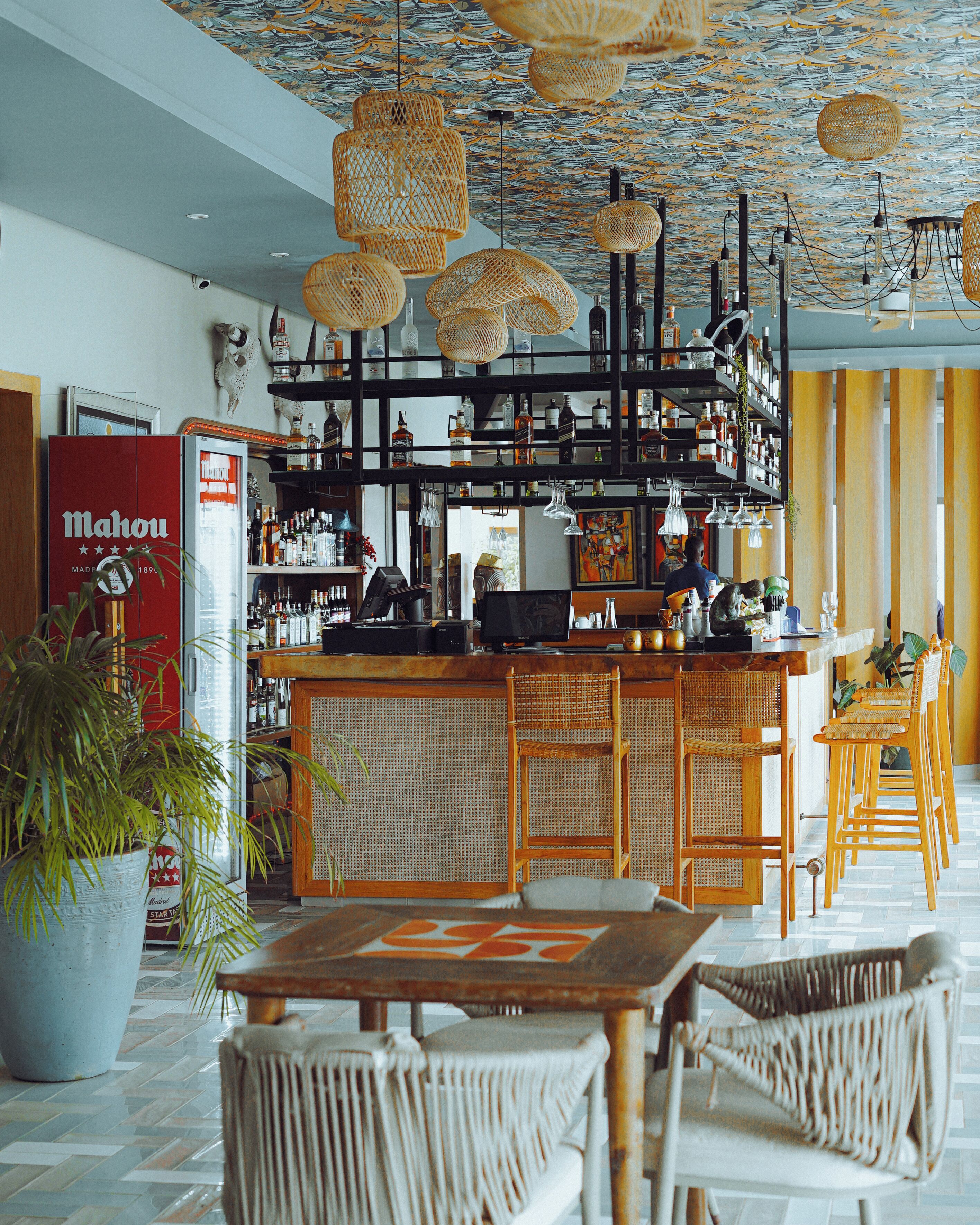 A bar area with wicker chairs, a bar counter, and shelves of liquor bottles.