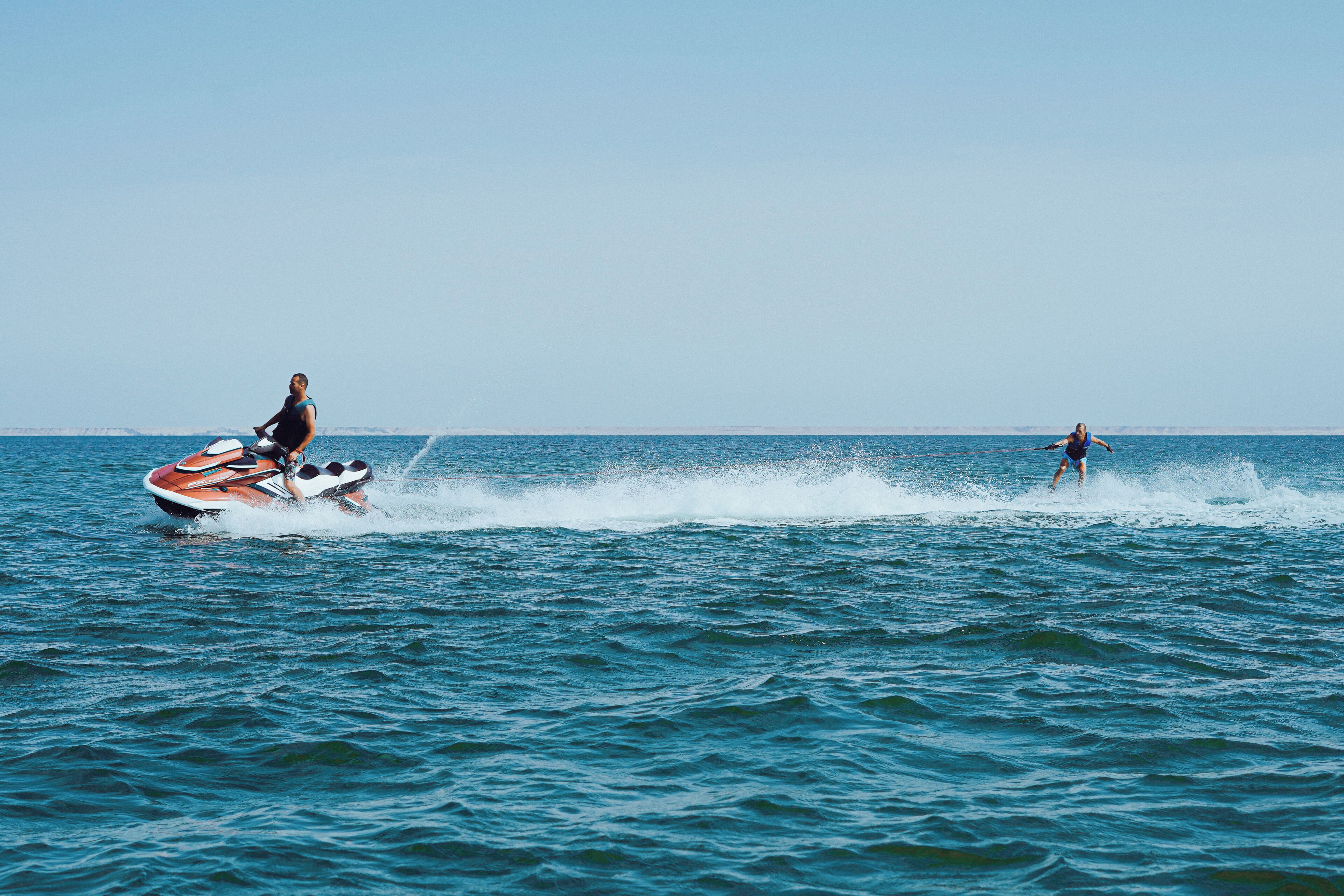 A person jet-skiing on a body of water with a boat nearby.