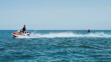 A person jet-skiing on a body of water with a boat nearby.