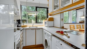 A modern kitchen with white cabinetry, a built-in washing machine, and a large window providing a view of the outdoors. - Lovely home in Væggerløse with kitchen (Væggerløse)