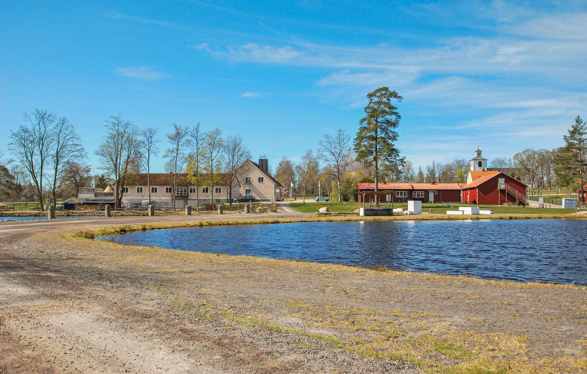 Une propriété située au bord d’un lac, comprenant une grande maison, une grange rouge et une église.