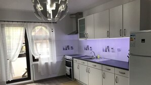 Une cuisine moderne avec des meubles blancs, un four encastré, un évier et un réfrigérateur.