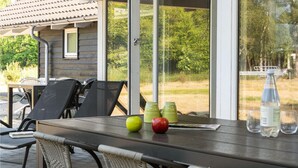 Un patio con mesa, sillas y vistas a una casa y árboles.