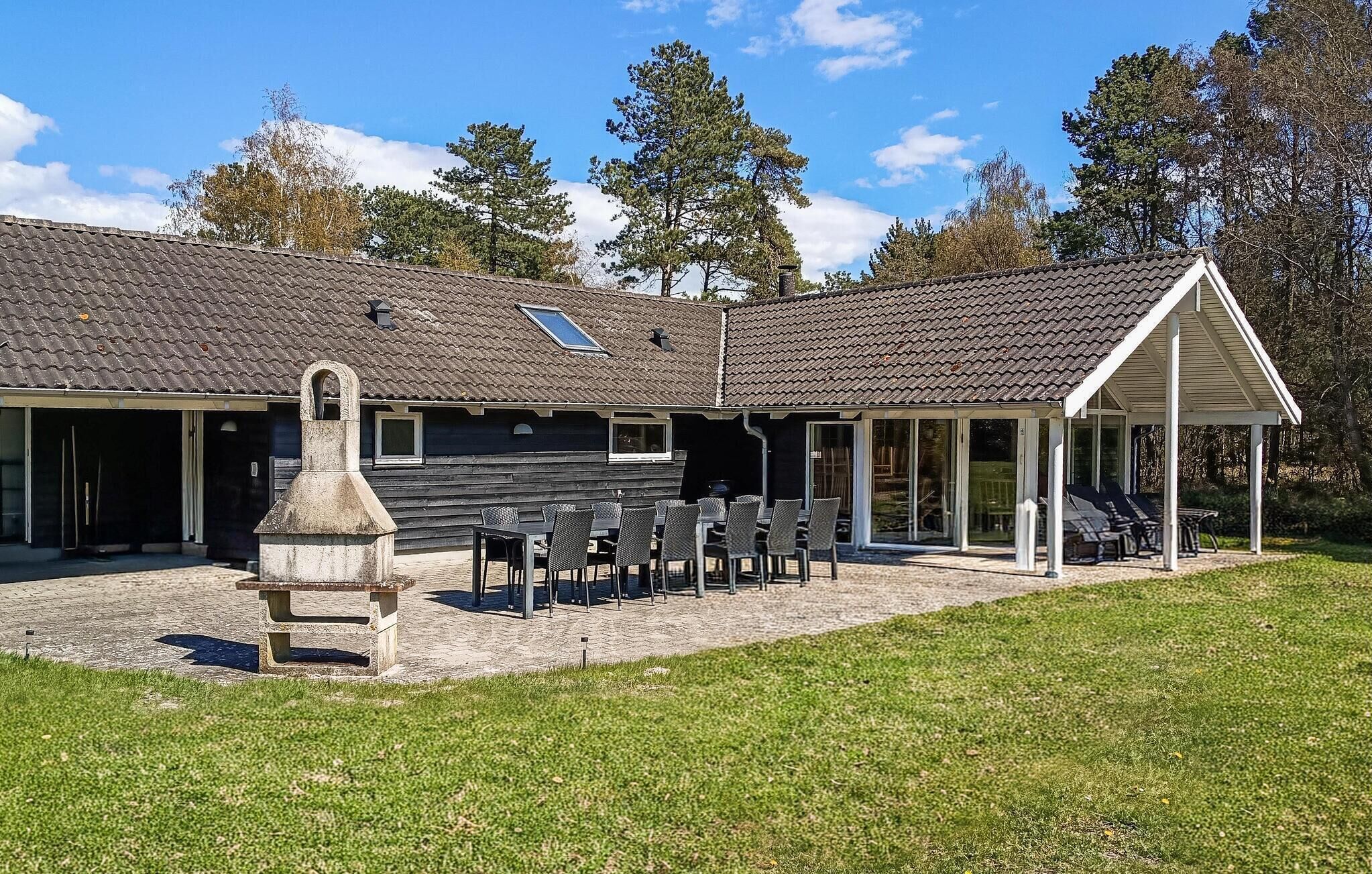 A building with a tiled roof, a covered patio with outdoor seating, and a stone structure in the foreground.