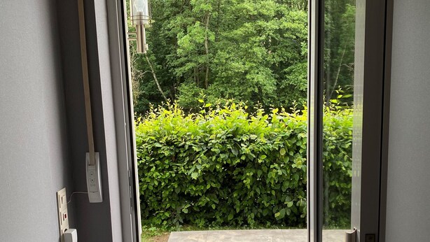 A door leading to a patio with a hedge and a tiled floor. - beautiful, very quiet apartment with terrace  (Winterberg)