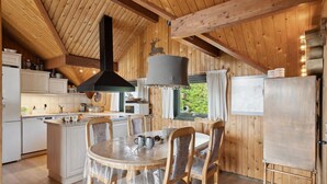 Een houten interieur met een keuken, een eetgedeelte en een groot raam met gordijnen.