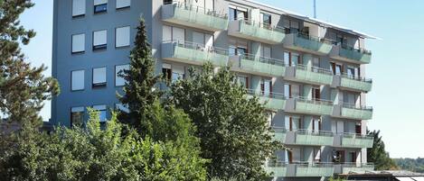 Un immeuble résidentiel à plusieurs étages, doté de balcons, d’un toit plat et surplombant un ciel dégagé.