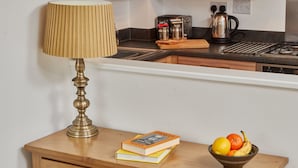Une cuisine avec un plan de travail en bois, une lampe en laiton, un livre et un saladier rempli de fruits.